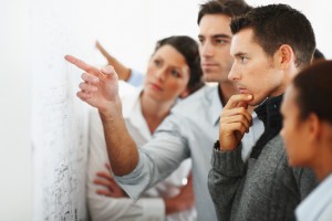 Group of business people looking at a chart put up on the wall